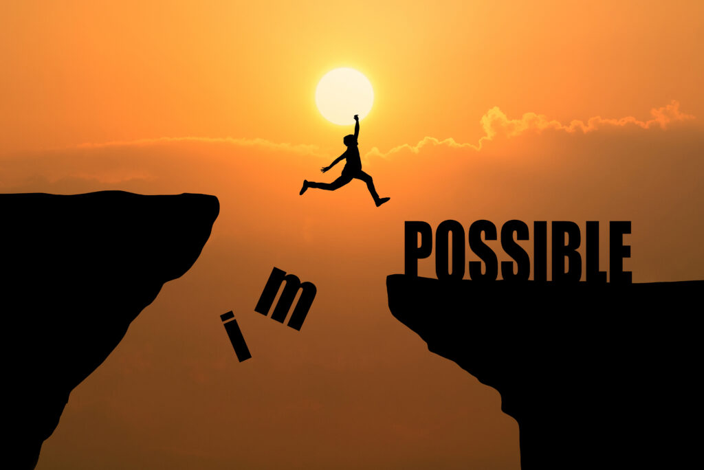 Man jumping over impossible or possible over cliff on sunset bac